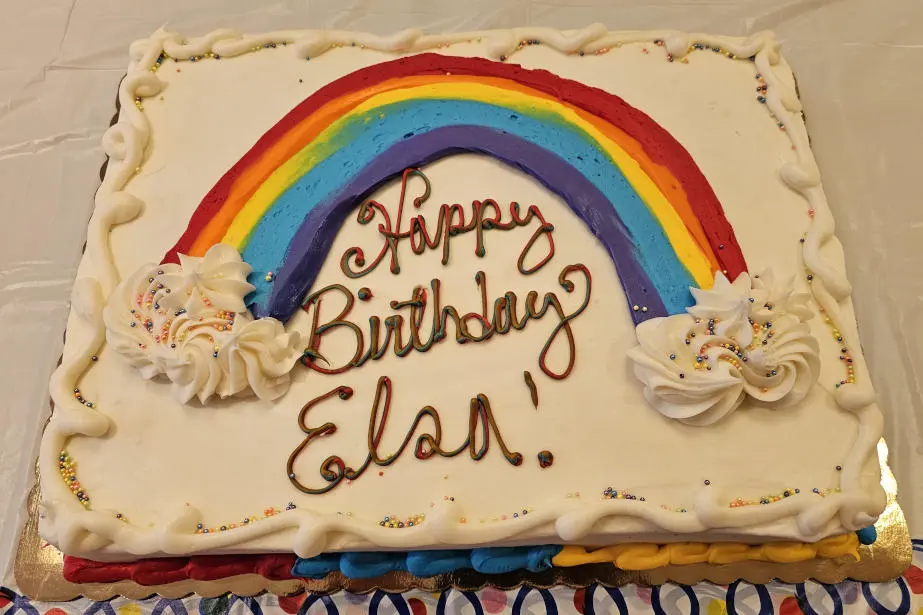 A half sheet cake with a big rainbow in the center.